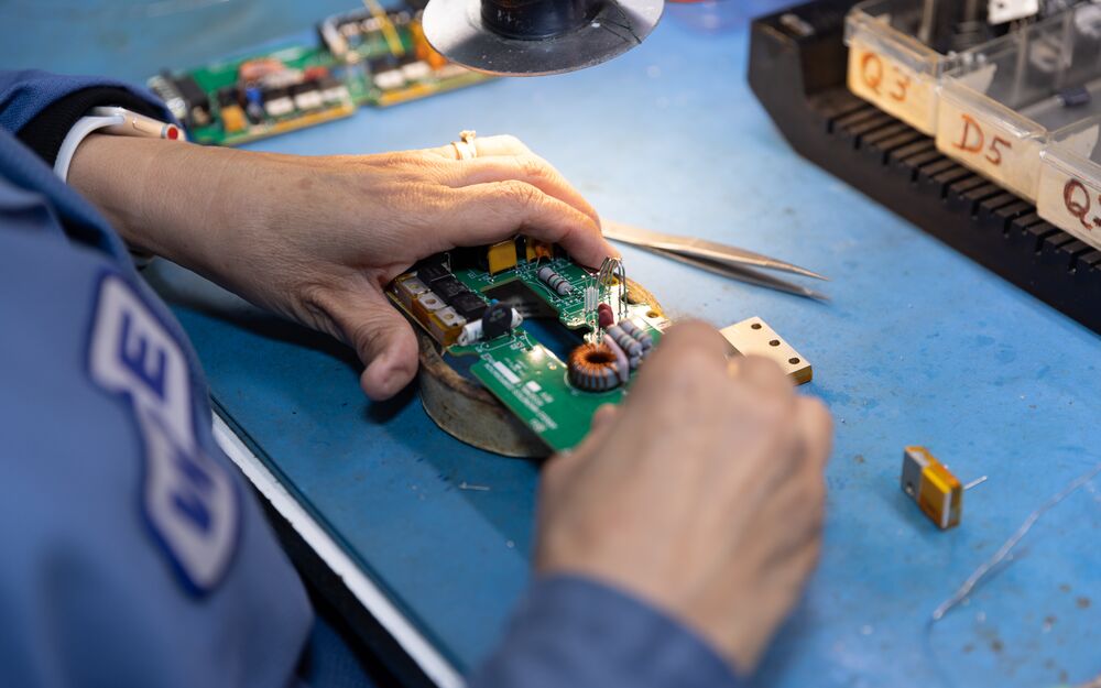 WCE technician hand-assembling a populated circuit board